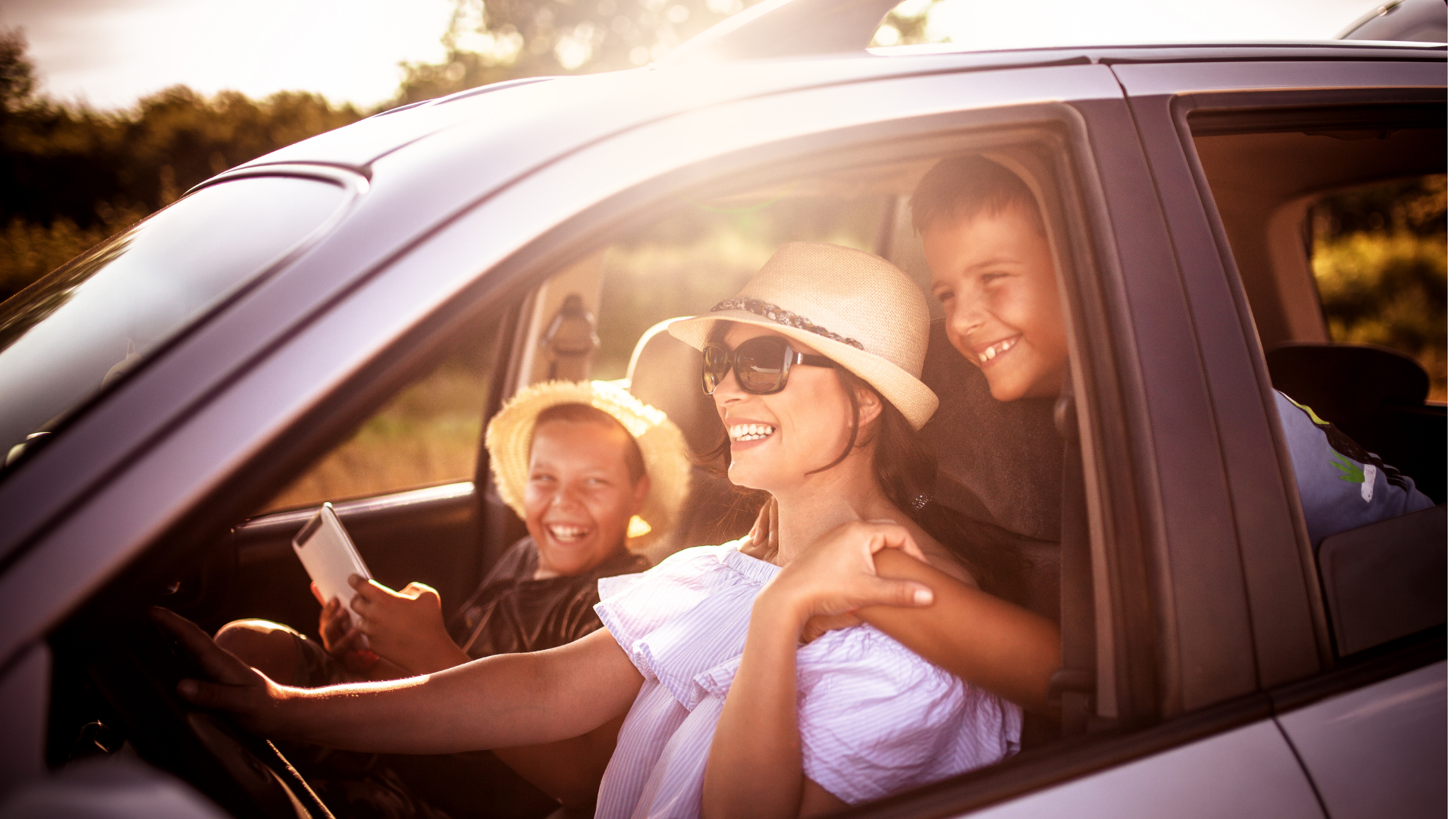 Woman driving car on sunny day with laughing children