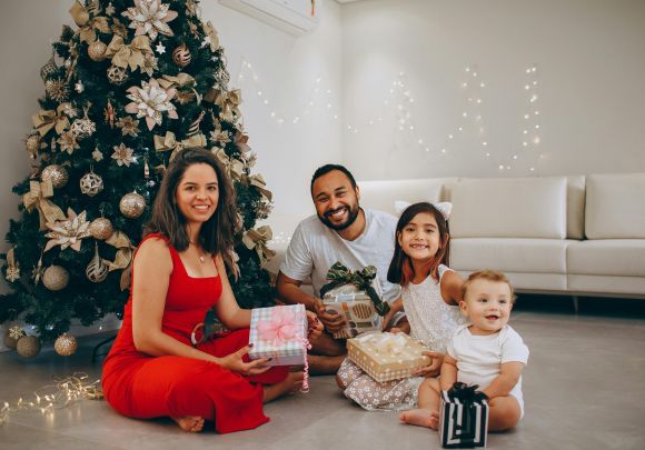 Young couple with young children in front of christmas tree